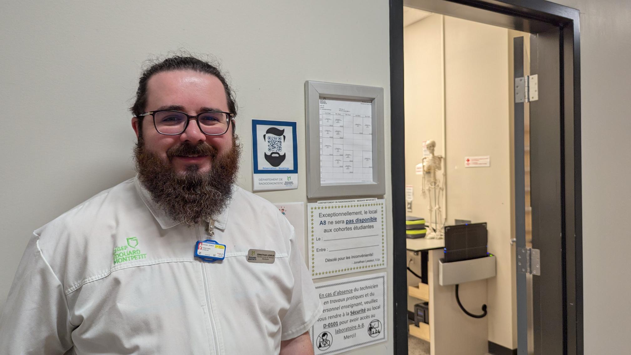 Technologue en travaux pratique se situant à côté d'un code QR pour réservation par Bookings qui se trouve à côté de la porte d'accès au laboratoire.